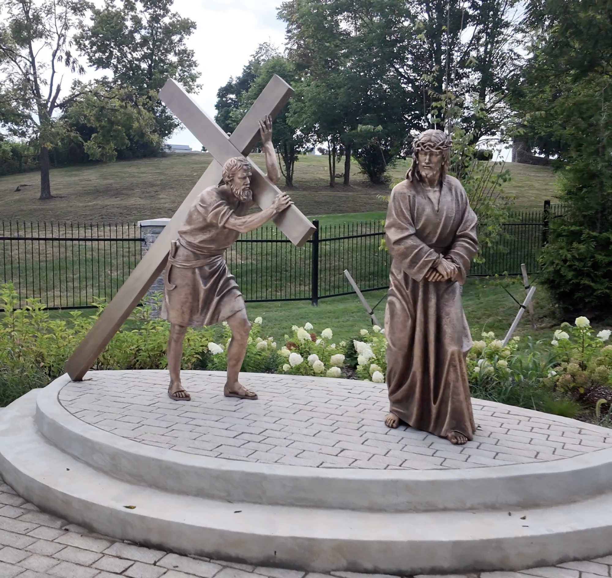 Bronze sculpture of Simon of Cyrene helping carry the cross — Station V of the Stations of the Cross at the Gardens at St. Patrick’s.